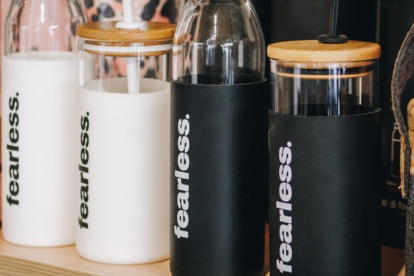 A row of black and white drink bottles branded with the Fearless logo. Fearless is a Wanaka exercise gear store.