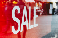 sale sign reflecting shoppers on street