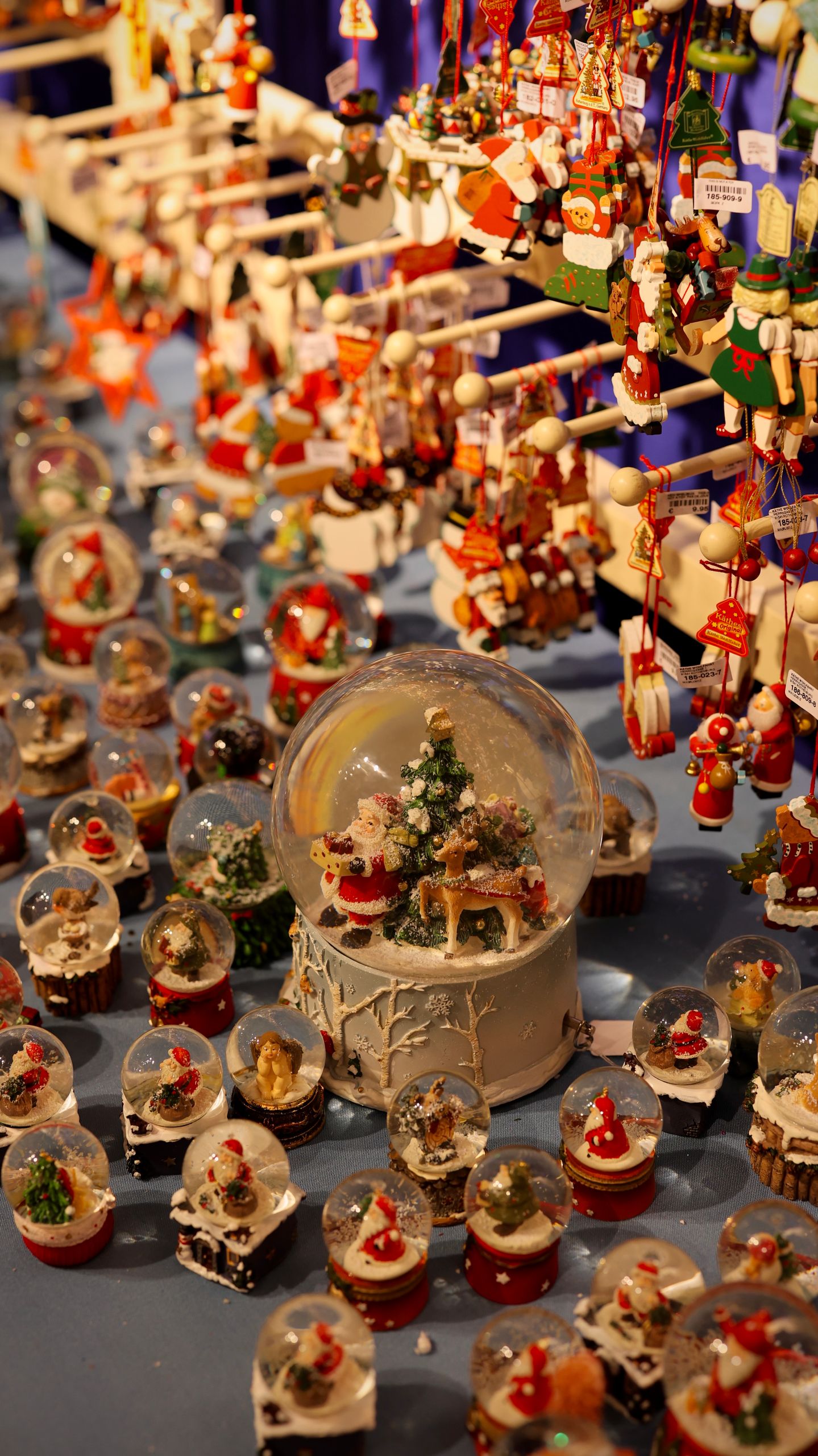 A vibrant collection of Christmas snow globes and hanging ornaments at a festive market stall.